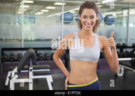 Fit Woman messen ihre Taille und Daumen auftauchen Stockfoto