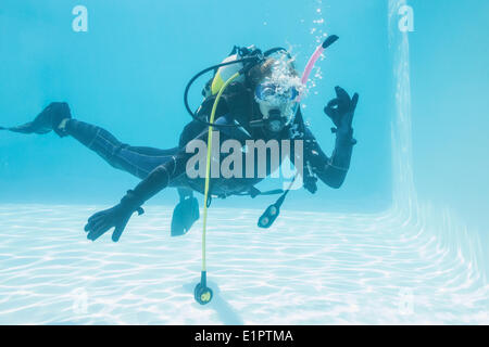 Frau auf Tauchausbildung untergetaucht im Schwimmbad machen ok Sign. Stockfoto