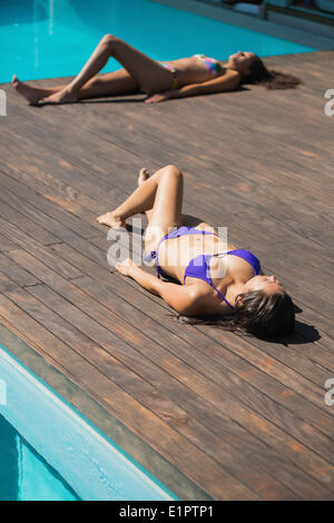 Frauen in Bikinis, die liegen am Pool sonnen Stockfoto