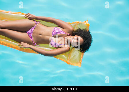 Glückliche Frau liegend auf Lilo im Schwimmbad Stockfoto