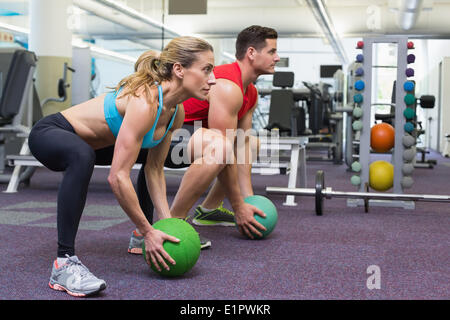 Bodybuilding-Mann und Frau heben Medizinbälle Kniebeugen machen Stockfoto