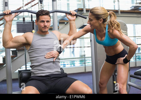 Bodybuilder mit Gerät für Krafttraining für Arme mit ermutigenden Trainer Stockfoto