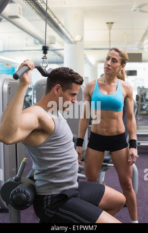 Bodybuilder mit Gerät für Krafttraining für Arme mit ermutigenden Trainer Stockfoto