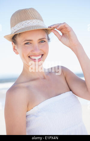 Ziemlich lächelnde Blondine am Strand tragen Strohhut Stockfoto