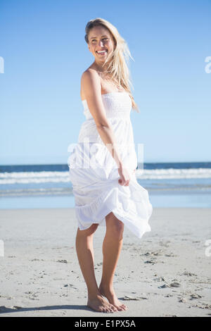 Frau in weißem Kleid lächelnd am Strand Stockfoto