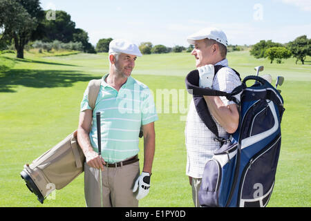 Golfer-Freunden chatten und halten ihre Golfbags Stockfoto