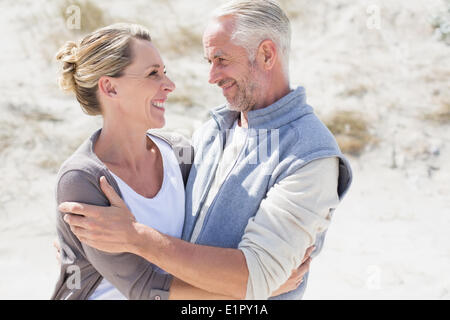 Brautpaar am Strand sahen einander umarmen Stockfoto