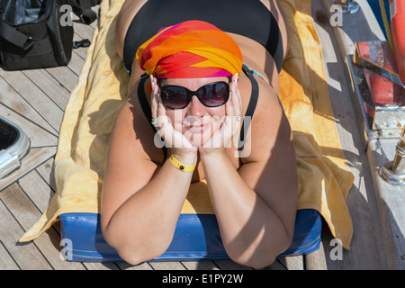Junge dicke Frau liegt auf dem Bauch auf dem Deck der Yacht Meer. Stockfoto