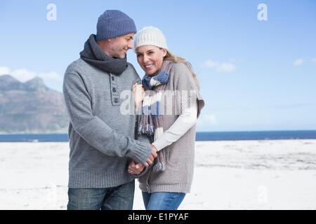 Lächelnde paar stehen am Strand in warme Kleidung Stockfoto