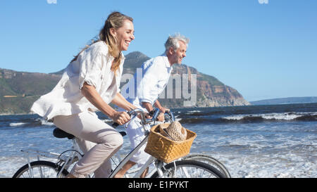 Lächelnde paar ihre Fahrräder am Strand Reiten Stockfoto