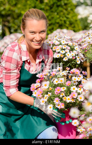 Garten-Center Arbeitnehmerin hält Rosa Topfblumen lächelnd sonnig Stockfoto