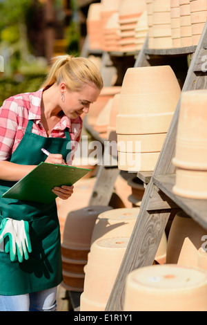 Garten-Center Arbeitnehmerin Notizen von Ton-Töpfe-Regal Stockfoto