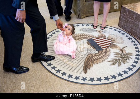 US-Präsident Barack Obama reicht bis zum 6-Monate-alten Sabina Johnson sitzt auf dem Präsidenten-Siegel bei einem Besuch in das Oval Office mit ihrem Onkel, Elbek Elibaev für seinen Make-A-Wish-Besuch im Weißen Haus 11. April 2014 in Washington, DC. Stockfoto