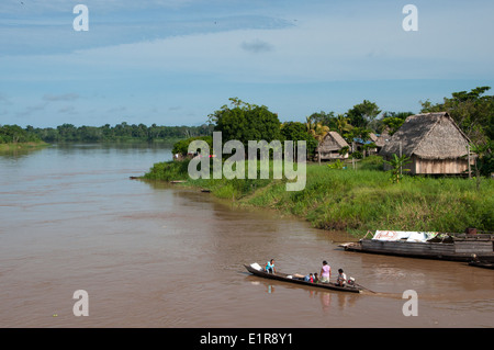 Familie auf einem kleinen Flussboot vorbei Dorf auf dem peruanischen Amazonas Stockfoto