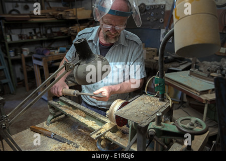 Gealterte Mann prüft der hausgemachten Drehbank Drehstahl beim Schleifen aus Holz waren. Stockfoto