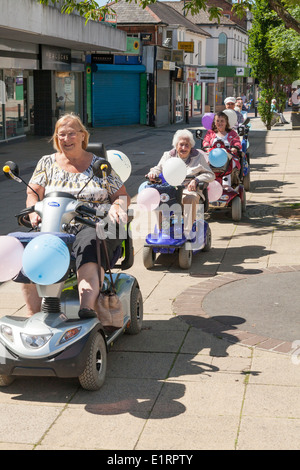 Gruppe von Menschen tun ein Charity-Volkslauf zugunsten von Southampton Krankenhaus auf dekoriert Mobilität Roller. Stockfoto