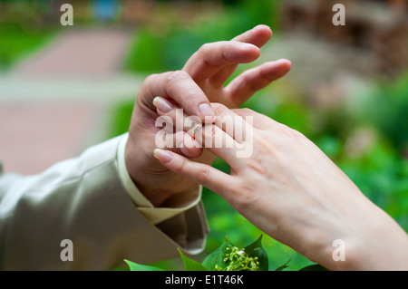 Mannes hand setzen Ehering in Frauenhand Stockfoto