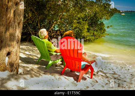 Anonymes Seniorenpaar, das die Aussicht von ihren farbenfrohen Liegen am Wasser an einem weißen Sandstrand an der Golfküste Floridas genießt Stockfoto