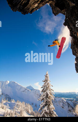 Eine männliche Snowboarder fängt einige von einer Klippe auf seinem Splitboard in Revelstoke Mountain Resort Backcountry, Revelstoke, BC Stockfoto