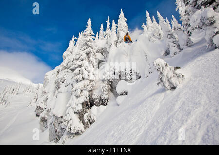 Eine männliche Snowboarder fängt einige von einer Klippe in Revelstoke Mountain Resort Backcountry, Revelstoke, BC Stockfoto