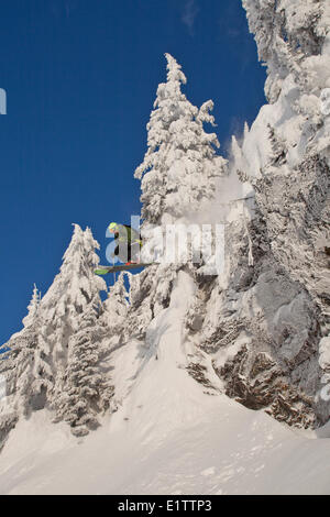 Ein männlicher Skifahrer fängt etwas Luft von einer Klippe in Revelstoke Mountain Resort Backcountry, Revelstoke, BC Stockfoto