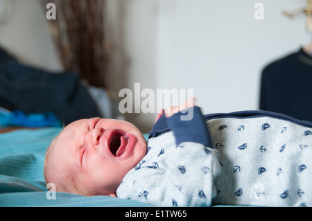 Baby weint auf einer weichen Decke mit beweglichen Armen Stockfoto