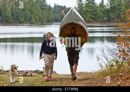 Junges Paar Portage Kanu aus kleinen See im nordwestlichen Ende des Algonquin Park, Ontario, Kanada. Stockfoto