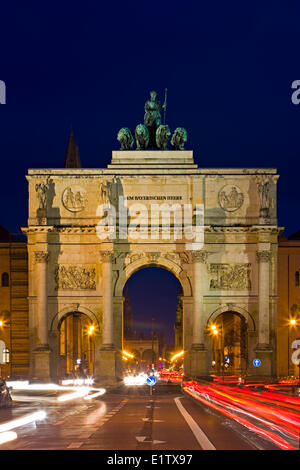 Das Siegestor (Siegestor) mit Datenverkehr um ihn herum in der Abenddämmerung im Stadtteil Schwabing in der Stadt München (München) Stockfoto