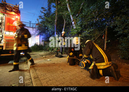 Düsseldorf, Deutschland. 10. Juni 2014. Feuerwehrleute sichern eine Unfallstelle in Düsseldorf, 10. Juni 2014. Drei Menschen sind gestorben, nachdem ein Baum in einem Gartenhäuschen während des letzten Sturms am Montagabend 9. Juni 2014 stürzte. Foto: Roland Weihrauch/Dpa/Alamy Live News Stockfoto