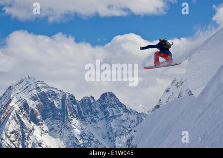 Ein männlicher Backcountry-Snowboarder lüftet eine Kissen mit klassischen kanadischen Rockies Landschaft als Kulisse. Eisfall Lodge, Golden, BC Stockfoto