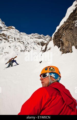 Zwei männliche Backcountry Skifahrer Bootpack auf einem steilen und ausgesetzten Coulior auf Mt. Patterson, Icefields Parkway, Banff, AB Stockfoto