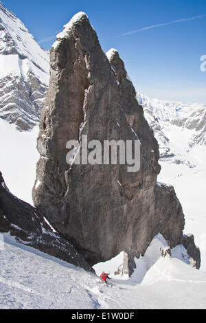 Ein männlicher Backcountry Skifahrer auf Tele Ski Tropfen in einem steilen Couloir mit einem einzigartigen Kalkstein Bogen drin. Mt. Französisch Peter Lougheed Stockfoto