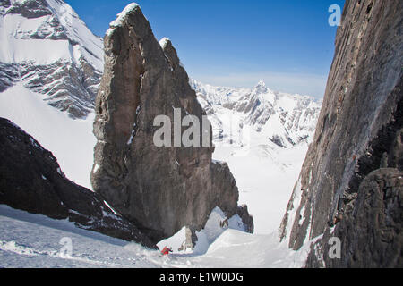 Ein männlicher Backcountry Skifahrer auf Tele Ski Tropfen in einem steilen Couloir mit einem einzigartigen Kalkstein Bogen drin. Mt. Französisch Peter Lougheed Stockfoto