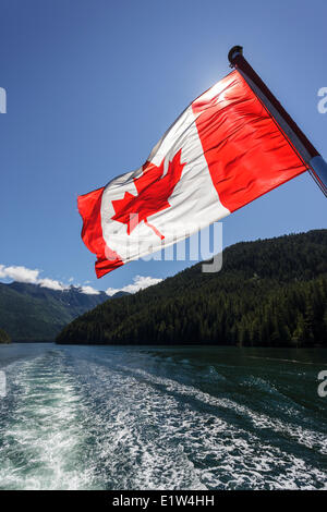Die kanadische Flagge fliegt aus dem Heck des Uchuck 111, wie es Esperanza Inlet, British Columbia, Kanada durchläuft. Stockfoto