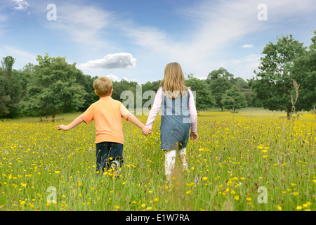 Bruder und Schwester, die Hand in Hand gehen durch ein Tasse butter Stockfoto