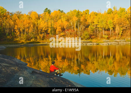 Wanderer entspannt auf präkambrischen Schild Felsen entlang des Winnipeg River, in der Nähe von sieben Schwestern, Manitoba, Kanada Stockfoto