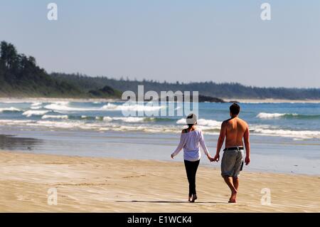 Ein junges Paar gehen Hand in Hand auf Long Beach im Pacific Rim National Park in der Nähe von Tofino, BC. Stockfoto