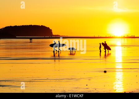 Surfer unterwegs bei Sonnenuntergang auf Chesterman Beach in Tofino, BC. Stockfoto