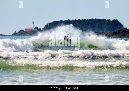 Eine Surfer macht einen Schnitt während auf einer Welle an Cox Bay in Tofino, BC. Stockfoto