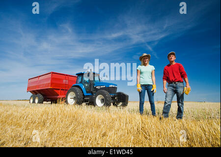 Vater Bauernmädchen stehend in Hafer Stoppeln vor einen Traktor Getreide Wagen während der Ernte in der Nähe von Dugald Manitoba Kanada Stockfoto
