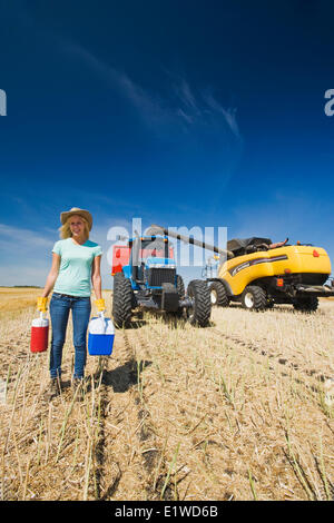 ein Bauernmädchen in Hafer Stoppeln stehen vor ein Traktor Getreide Wagen kombinieren, während der Ernte in der Nähe von Dugald Manitoba Kanada Stockfoto