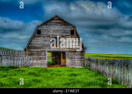 Alte Scheune neben Alberta Highway #21 mit grünem Rasen, blauer Himmel und Wolken und Zaun. In der Nähe von Strathmore, Alberta, Kanada. HDR Stockfoto