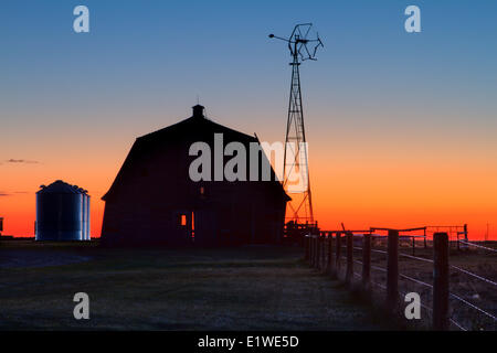 Sonnenaufgang am alten Scheune Hof mit Windmühle. Carsland, Alberta, Canaada Stockfoto