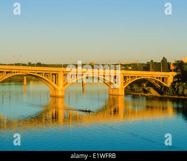 Ruderer bei Sonnenaufgang Rudern unter dem Broadway Bridge, South Saskatchewan River, Saskatoon, Saskatchewan, Kanada Stockfoto