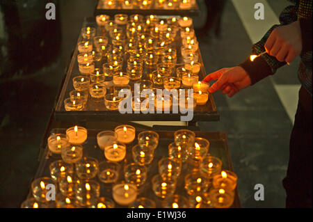 Aperson Anzünden einer Kerze in einer Kirche in Brügge, Belgien Stockfoto