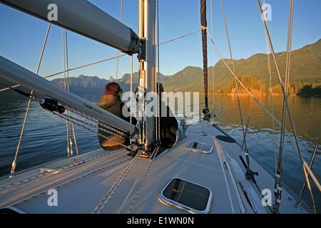 zwei Frauen sitzen an Deck des Segelbootes in Desolation Sound den Sonnenuntergang auf Mountains, British Columbia, Kanada, Darrel Gie Stockfoto