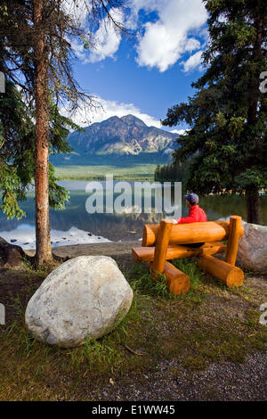 Mittleren Alters Männchen sitzen auf der Bank am Pyramid Lake betrachten Pyramide Berg, Jasper Nationalpark, Alberta, Kanada. Stockfoto