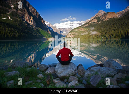 Mittleren Alters, Männlich meditieren auf Felsen am Lake Louise, Alberta, Kanada. Stockfoto