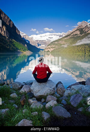 Mittleren Alters, Männlich meditieren auf Felsen am Lake Louise, Alberta, Kanada. Stockfoto