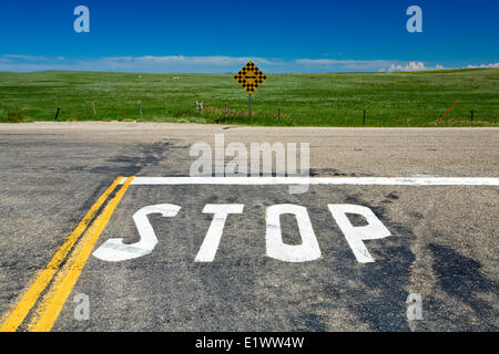 Stop-Schild gemalt auf Landstraße mit Richtung Zeichen, Süd-Alberta, Kanada. Stockfoto